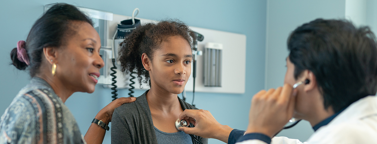 A girl and her mother speak to a doctor.